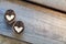 Two halves of split walnut with core in form of white hearts on wooden background, diagonal lines. Concept of