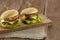 Two hamburger with cutlet grilled, lettuce, tomato, cheese, cucumber on a light wooden background