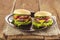 Two hamburger with cutlet grilled, lettuce, tomato, cheese, cucumber on a light wooden background