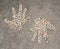 Two hand print designs made from small cream pebble stones in concrete pavement