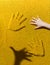 Two handprints on the yellow plastic pinscreen, children`s hand and hand shadow. Child playing with contact screen.