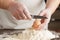 Two hands break an egg on wooden surface on a heap of flour