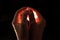 Two hands folded squeeze the light inside, reddish light inside the hands, black background.