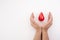 Two hands holding red blood drop on white background. Give blood. Donation concept.