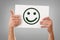 Two hands holding white sheet with happy face emoticon isolated