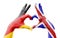 Two hands of a person painted with the flags of Germany and the UK forming a heart