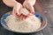 Two hands with rice grains over plate