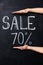 Two hands showing seventy percent sale drawn on blackboard