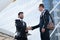 Two Handsome business man shaking hands outside modern office bu