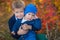 Two handsome cute brothers sitting on pumpkin in autumn forest alone