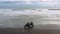 Two handsome hipster men riding modern custom motorcycle cafe racer on the black sand beach near the ocean. Adventure