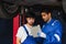 Two handsome male mechanics wearing uniform, using tablet, checking or inspecting for fix, repair car or automobile components,