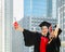 Two happiness graduated female in black graduation gowns holding diploma and hugging each other on graduation ceremony, standing