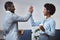 Two happy african american call centre telemarketing agents giving each other a high five and cheering with joy while