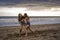 Two happy and attractive young Asian Chinese women girlfriends or sisters having fun playing wrestling on sunset beach in beautifu