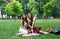 Two happy boho chic stylish girlfriends picnic in park