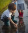 Two Happy Boy play in red paper ship in puddle summer day