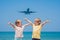 Two happy boys on the beach and a landing plane. Traveling with children concept