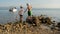 Two happy caucasian kids, brothers, playing together by throwing stones into the sea. Siblings playing outdoors at