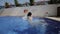 Two happy children, sisters are jumping into swimming pool at resort. Slow motion