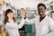 Two happy colleages pharmacists, African man and Caucasian woman working in drugstore, smiling. giving five and having