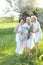 Two happy daughters standing with old mother outside and wearing white dresses.