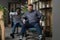 Two happy diverse male colleagues riding on chairs in office