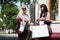 Two happy fashion women with shopping bags walking in city street