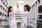 Two happy female colleages pharmacists, African and Caucasian women working in drugstore, smiling, giving five, looking