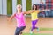 Two happy female fitness models dancing Zumba, doing aerobic exercises working out to lose weight in gym with colorful