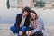 Two happy friends or sisters sitting on the floor and looking at the camera. Lifestyle outdoors. Port background