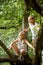 Two happy girls climbing up tree in summer park