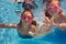 Two happy girls in goggles swimming under water