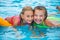 Two happy girls playing in the pool on a sunny day. Cute little girls enjoying holiday vacation