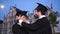 Two happy graduating students. Male graduate student helps the girl to straighten the cap. She smiles at him.