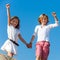 Two happy kids raising hands outdoors.