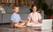 Two happy kids sitting in lotus pose and smiling while practicing yoga online
