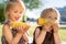 Two happy little childs girls sisters eat sweet corn cob at summer day. Healthy eating, picnic