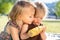 Two happy little childs girls sisters eat sweet corn cob at summer day. Healthy eating, picnic