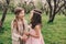 Two happy little girlfriends picking flowers in spring garden. Sisters spending time together outdoor.