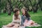 Two happy little girlfriends picking flowers in spring garden. Sisters spending time together outdoor.