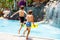 Two happy little kids boys jumping in the pool and having fun on family vacations in a hotel resort. Healthy children