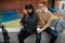 Two happy people in love sitting on a concrete border, looking at phone