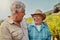 Two happy senior farmers standing and embracing on their vineyard. Smiling elderly Caucasian and mixed race men and