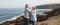 Two happy senior people standing on the cliff of the ocean.Hugging and smiling. Morning soon outdoor with clear sky. Vacation and