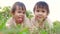 Two happy sibling girls lying on green grass outdoors in summer park.