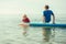 Two happy siblings teen children in neoprene suits having fun  with sup board in Baltic sea