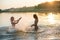Two happy slim young girls splashing in lake at