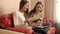 Two happy smiling schoolgirls smiling while sitting on sofa and writing in diaries