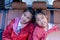 Two happy students smiling while enjoying road trip in car. Sisters smiling and looking camera inside car in morning. Asian